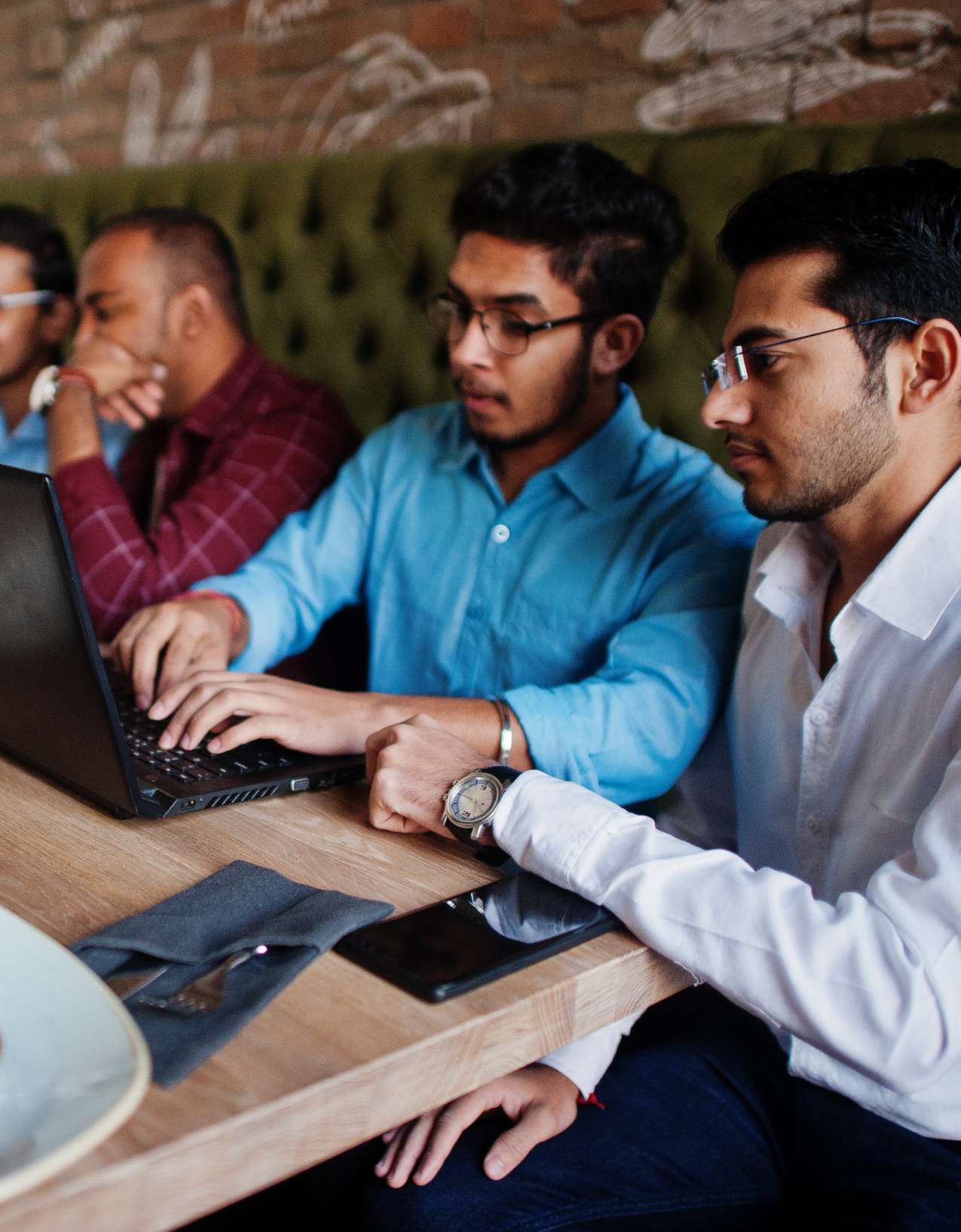 Diverse friendly coworkers talking using digital tablet in office.